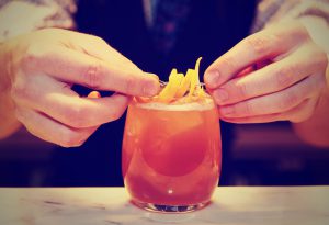 bartender adds garnish to pink cocktail